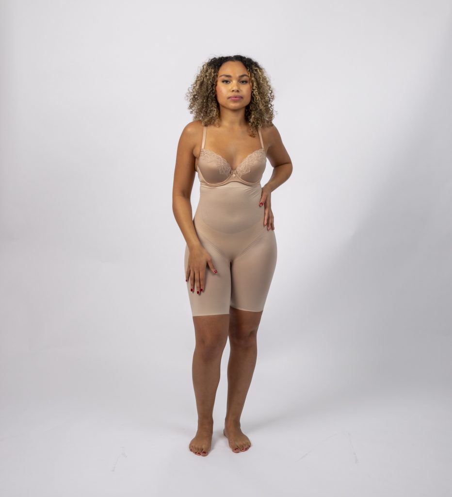 A poised woman models a versatile nude undergarment bodysuit from Deborah Winthrop Lingerie's curated collection.