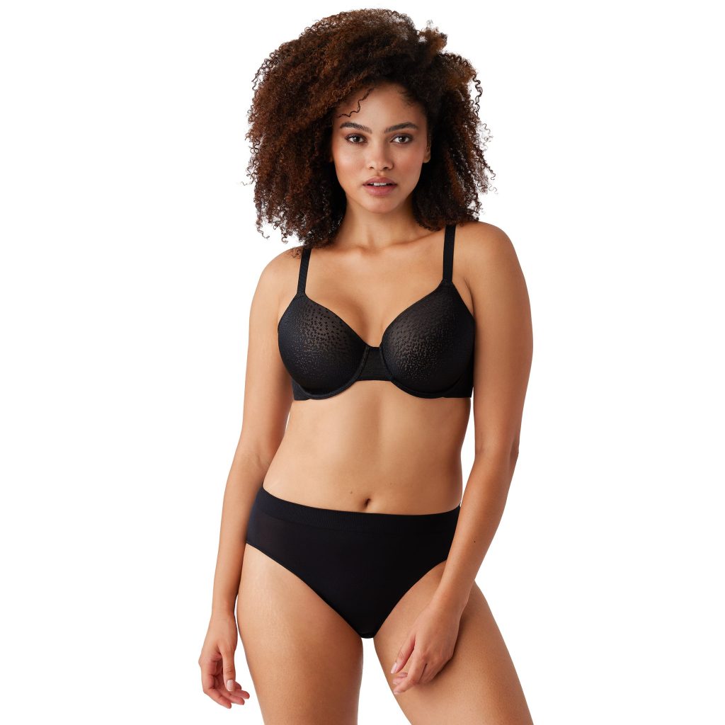 A confident woman in a black textured bra exemplifies the perfect fit offered by Deborah Winthrop Lingerie.